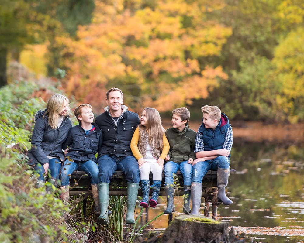 Family sitting on a jetty during an autumn family photoshoot in Sussex