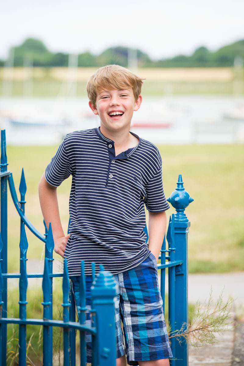 Young by leaning against a blue railing and smiling at the camera during the first of his family photoshoots in Sussex