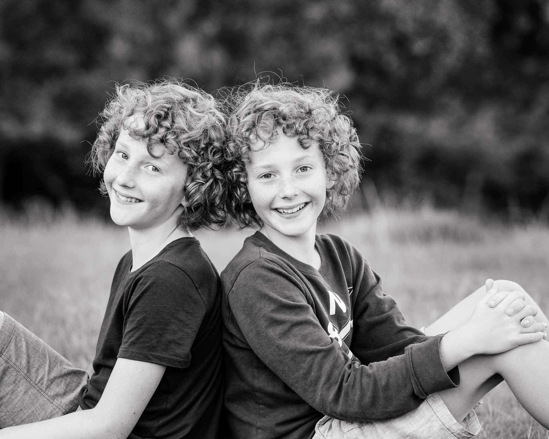 Black and white portrait of two brothers sitting back to back during a family photoshoot in Sussex