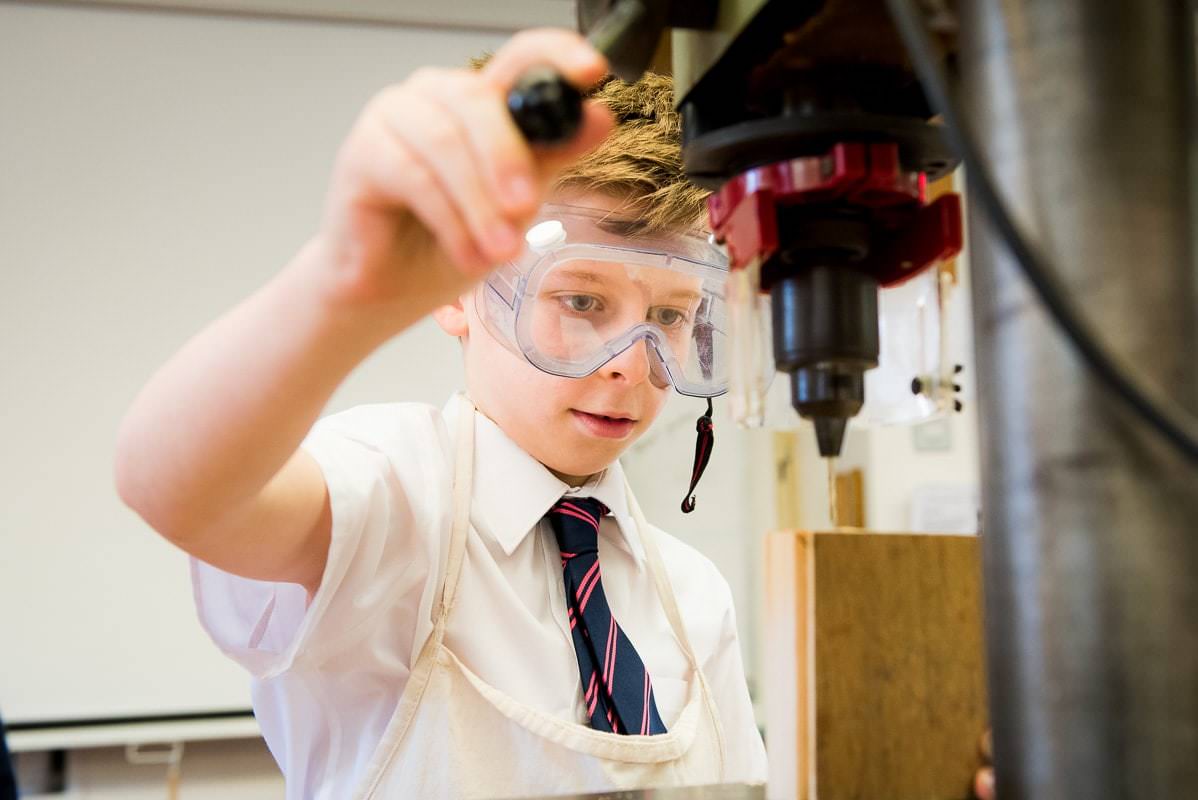Boy using drill in school during a school marketing photography shoot in Sussex