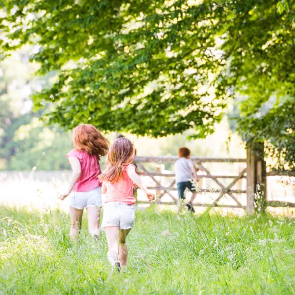 relaxed picture of 3 children running through summer meadow in West Sussex
