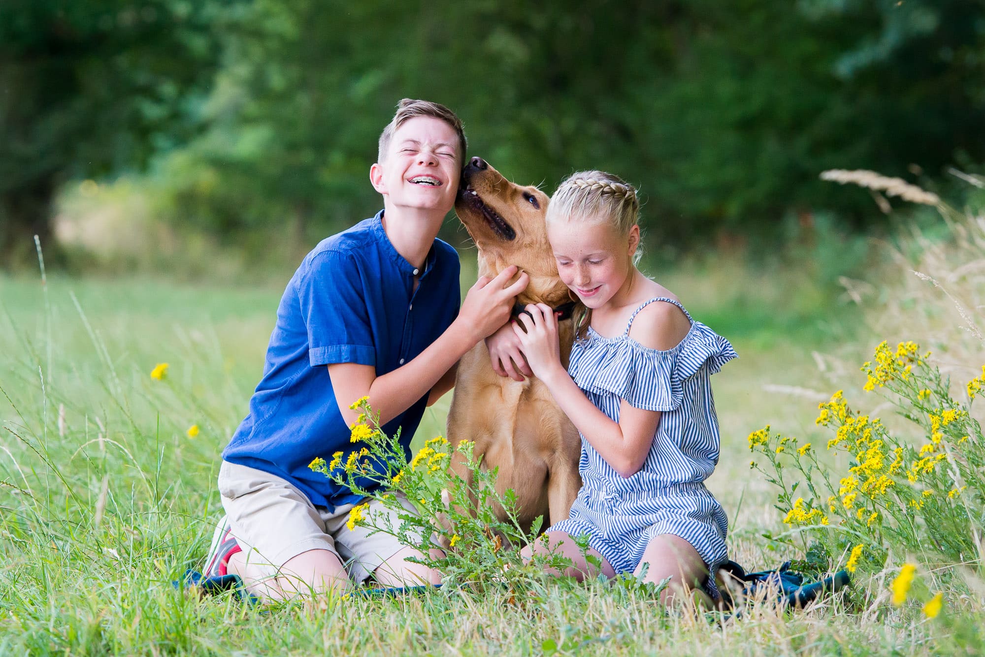 Two siblings cuddling their dog on a family photoshoot