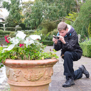 teenage boy photographing flowers at Borde Hill Garden, Sussex