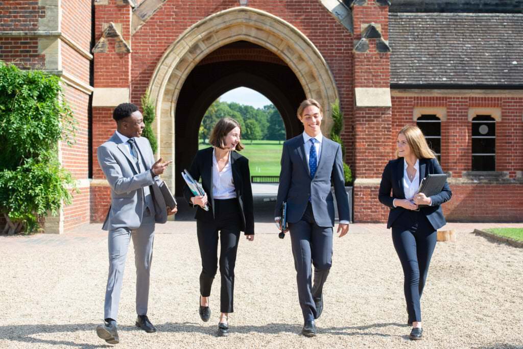 Group of teenage students walking through the arch of Ardingly College