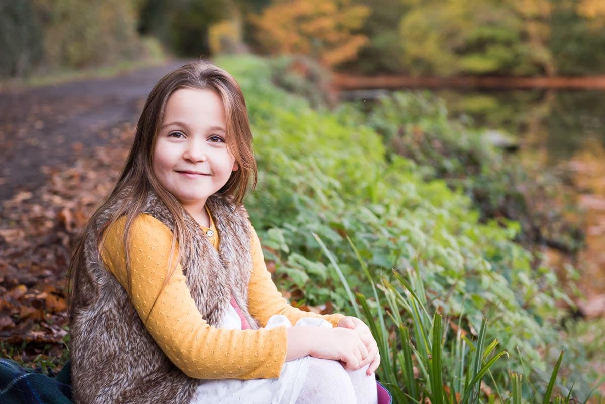 Young girl sitting outside wearing autumn coloured clothing