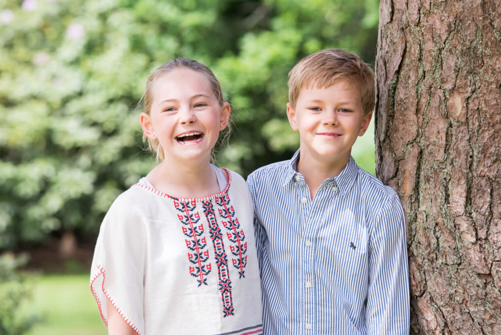A brother and sister pictured by a tree in their garden during a family photoshoot near Crowborough