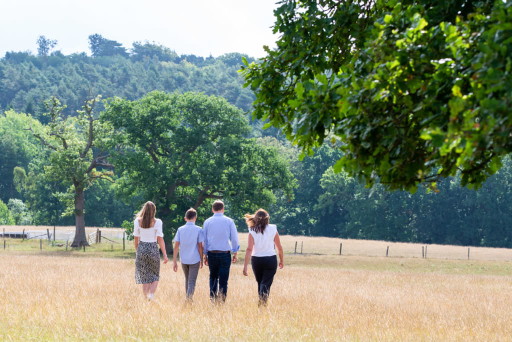 Family walking away from the camera in a meadow during a Worth Abbey family photoshoot