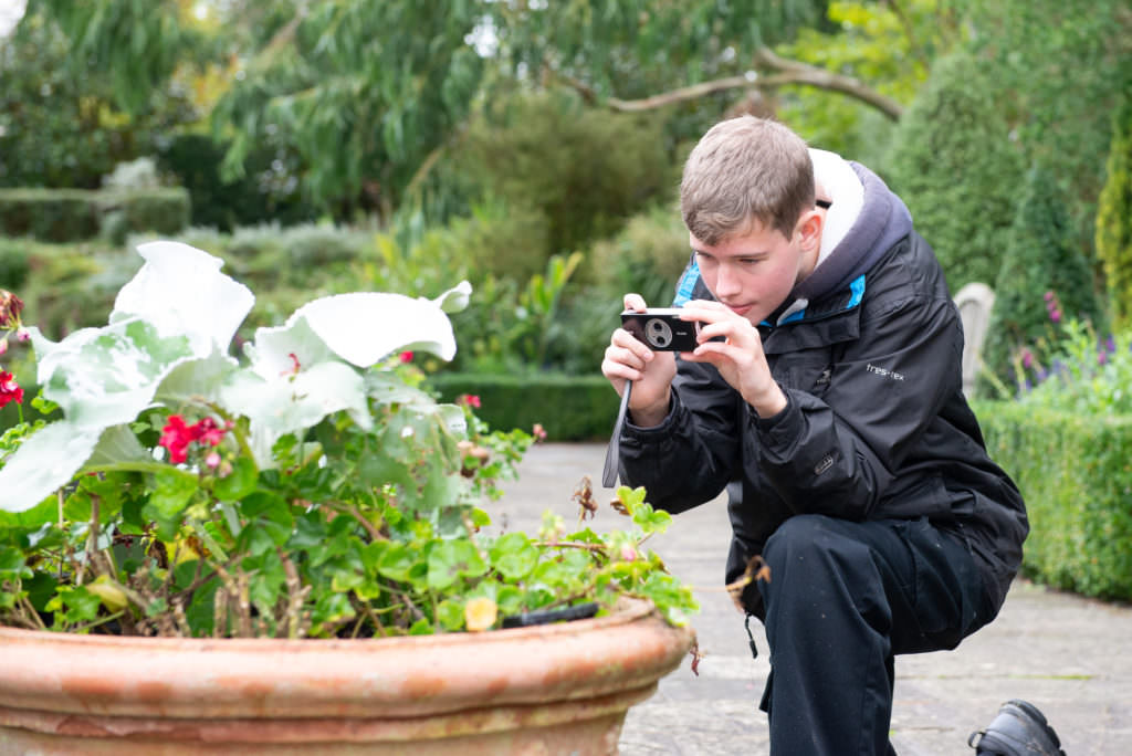 Health benefits of photography for teens, teenage boy photographing flowers at Borde Hill Garden, Haywards Heath