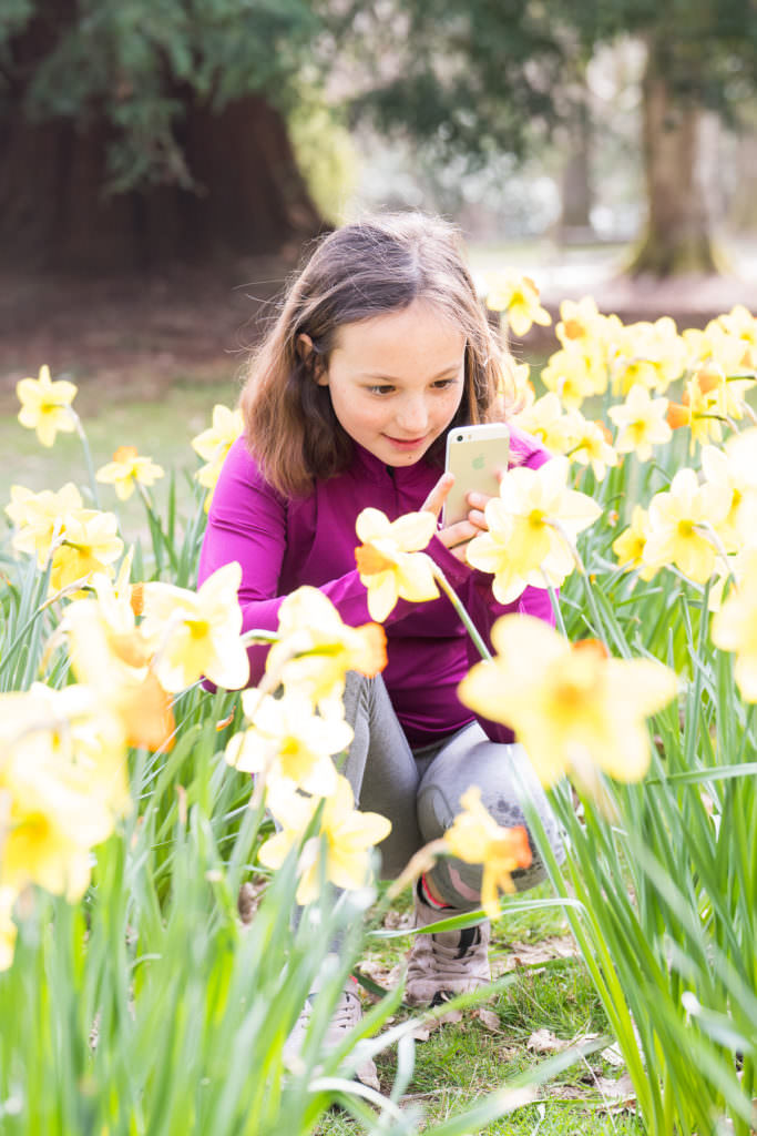 Young girl photographing daffodils on a photography course for children