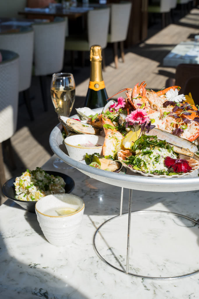 Seafood platter sitting on ice on a silver tray on a sunny restaurant table