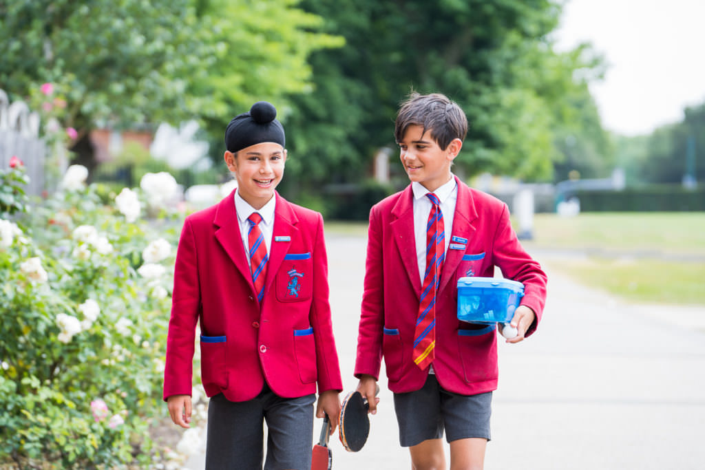 Two school boys wearing red blazers walking along a path during their lunch break, pictures taken on a school marketing photography photoshoot